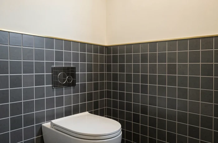 Carrelage mural bicolore en soubassement avec partie basse grise et peinture blanche au-dessus dans des toilettes
