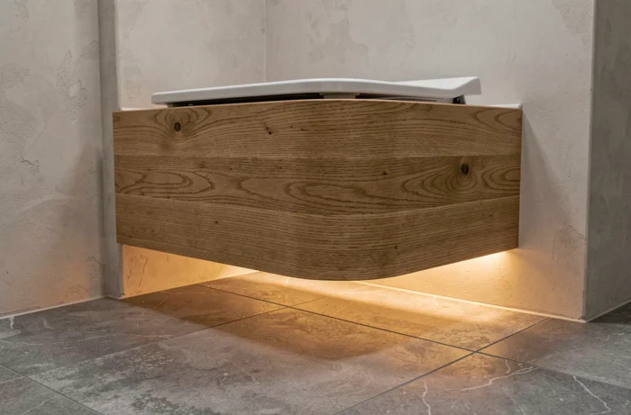 Éclairage indirect par bandeau LED sous le coffrage de toilettes suspendues avec halo chaleureux au sol