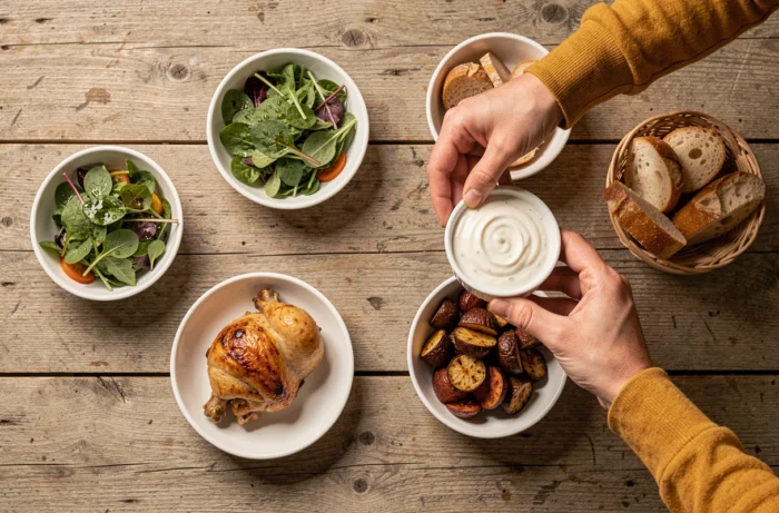 Vue de dessus d'un repas familial maison complet avec poulet rôti, salade et légumes sur une table en bois rustique