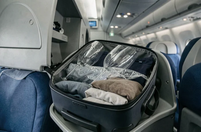 Valise cabine dans le compartiment supérieur d'un avion Air France avec de la vaisselle emballée à l'intérieur